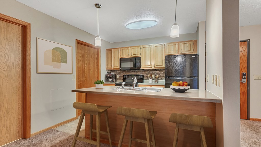 a kitchen with wooden cabinets and a counter with three bar stools