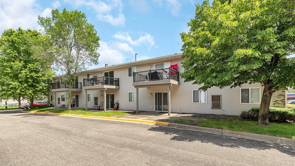 an apartment building with a street and trees in front of it