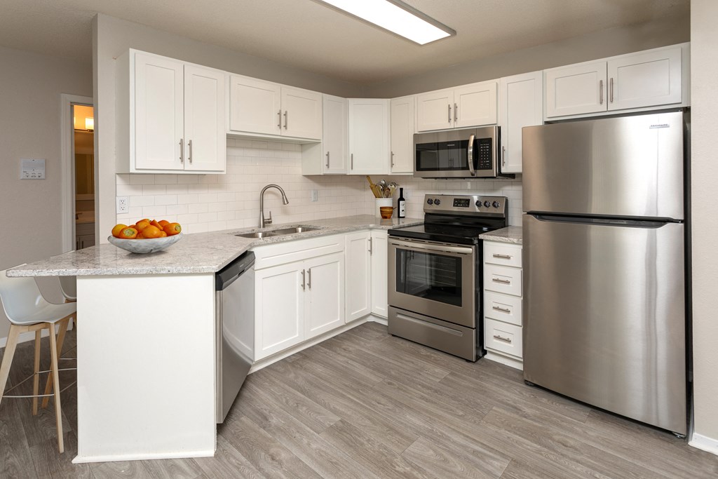 Kitchen with white cabinets, stainless steel appliances and grey wood floors