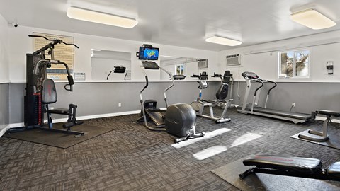 a gym with exercise machines and a tv on the wall