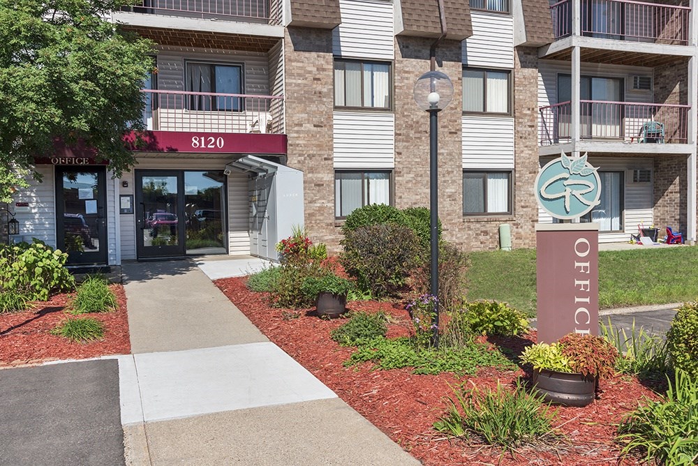 a sidewalk in front of an apartment building with a walkway and landscaping