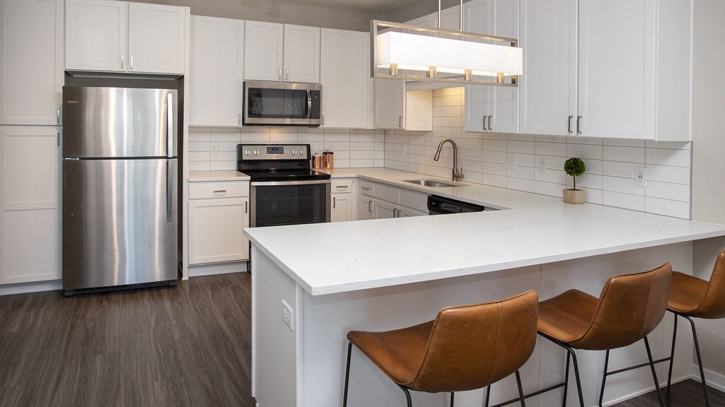a kitchen with a large island and a stainless steel refrigerator