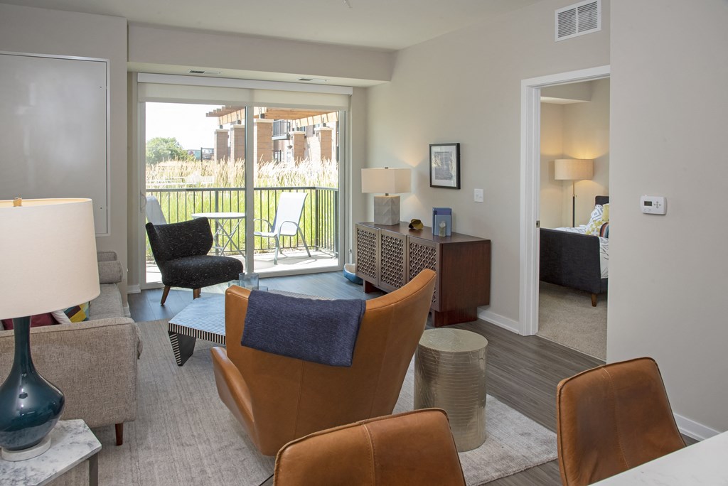 a living room with chairs and a table and a sliding glass door
