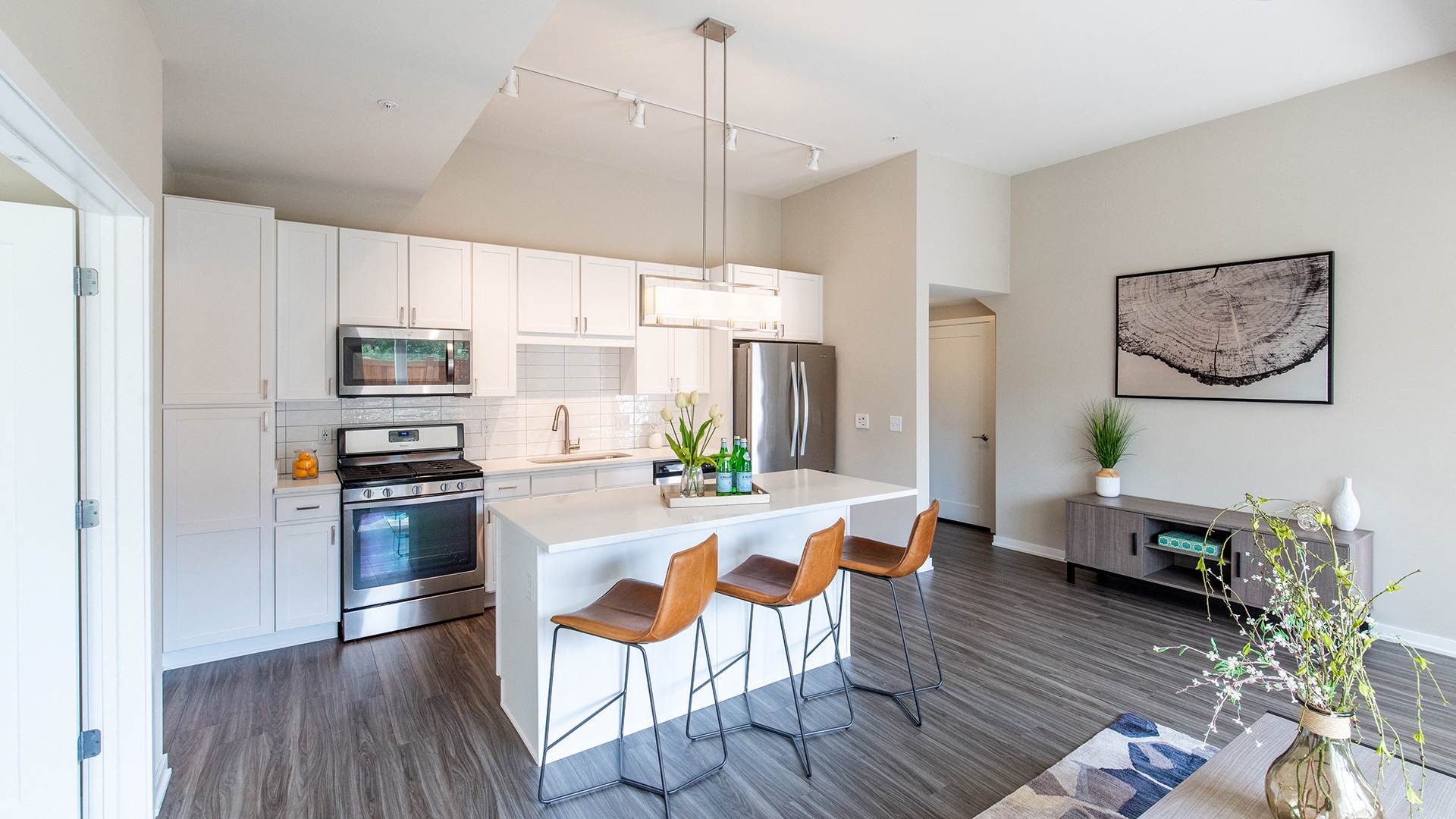 a kitchen with white cabinets and a white island with three chairs