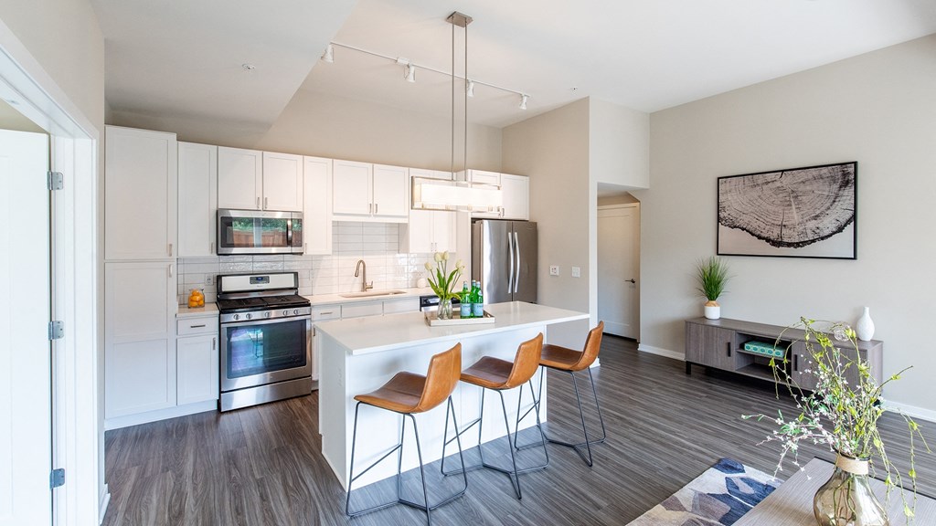 a kitchen with white cabinets and a white island with three chairs