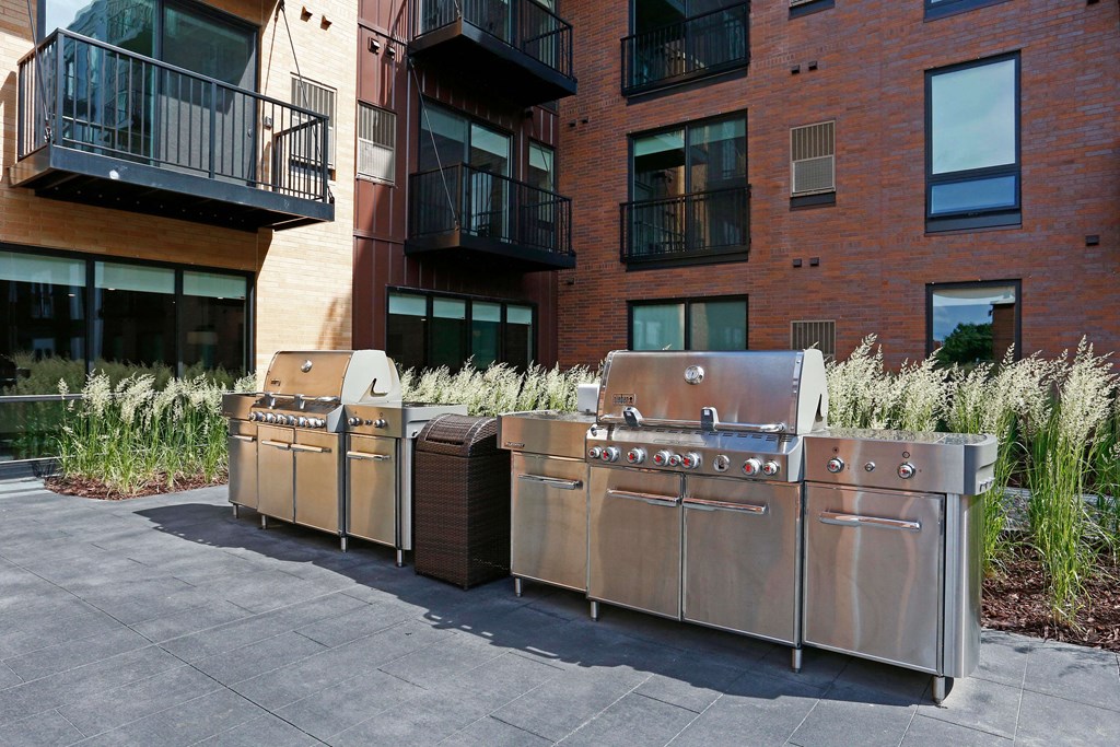 Outdoor grilling station with the exterior brick of Oxbo Urban Rentals behind.