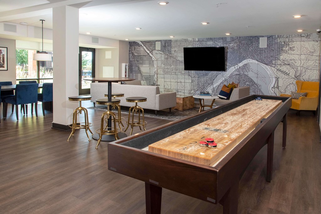 Large, bright clubroom complete with entertaining bar, shuffleboard, and TV lounge area with large glass doors looking out into the pool deck.