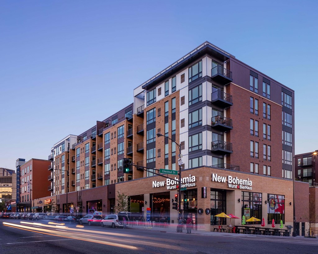 Exterior of Oxbo Urban Rentals with their large windows. Apartment units are located above a level of retail space, a restaurant on this level is New Bohemia.