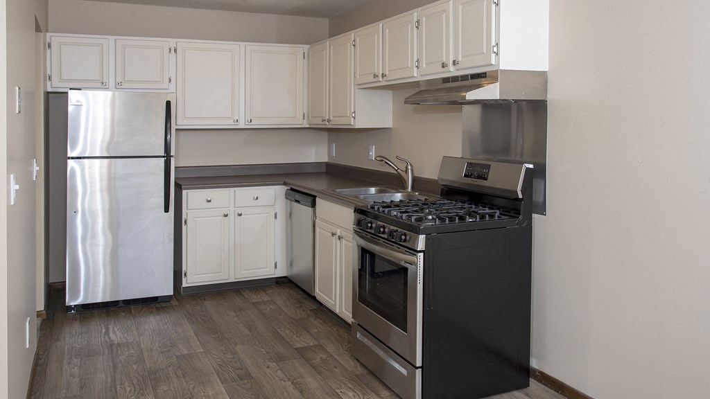 an empty kitchen with white cabinets and a stove and refrigerator