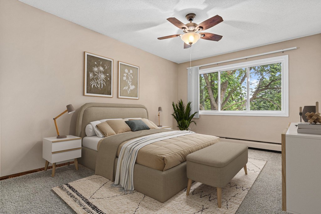 A bedroom with a bed, a bench, and a ceiling fan.