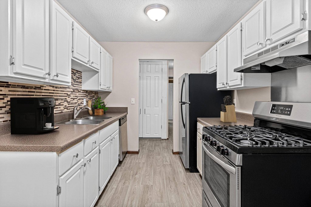 A kitchen with black appliances and white cabinets.