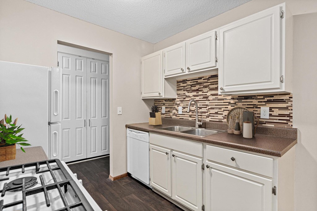 A kitchen with white cabinets and a white fridge.