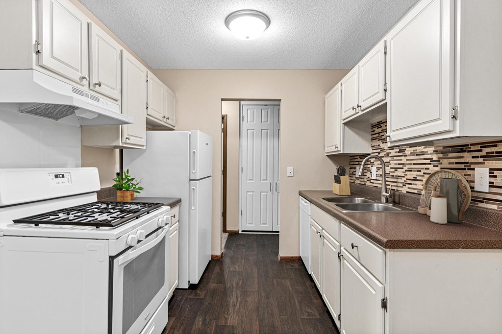 A kitchen with white appliances and cabinets.