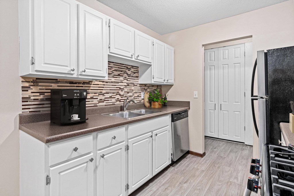 A kitchen with white cabinets and a black refrigerator.