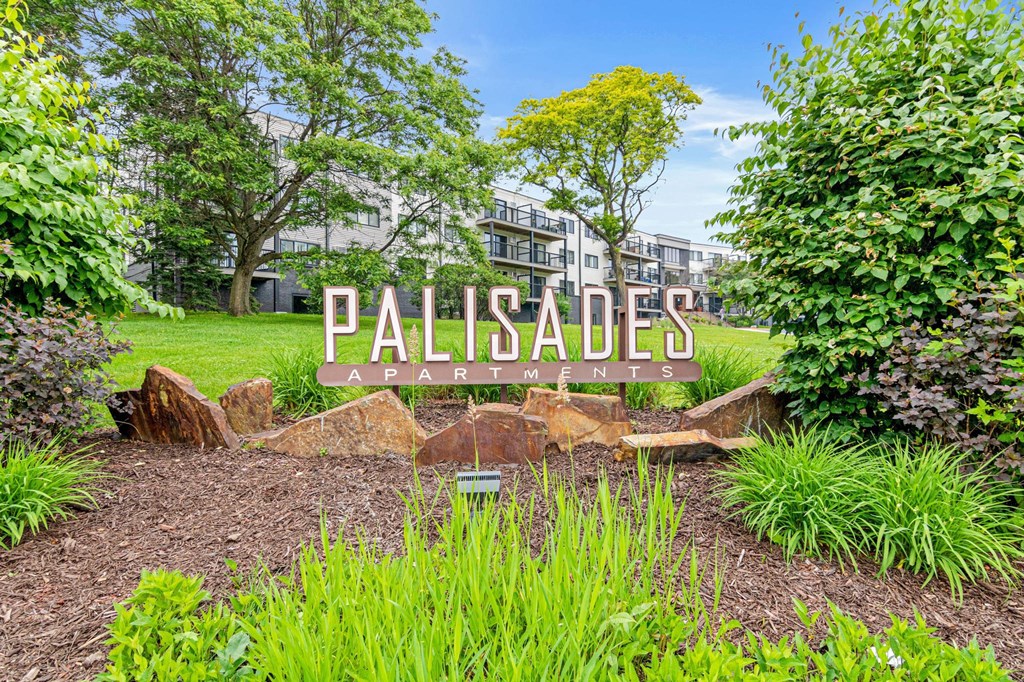 A garden with a sign that says Palisades Apartments.