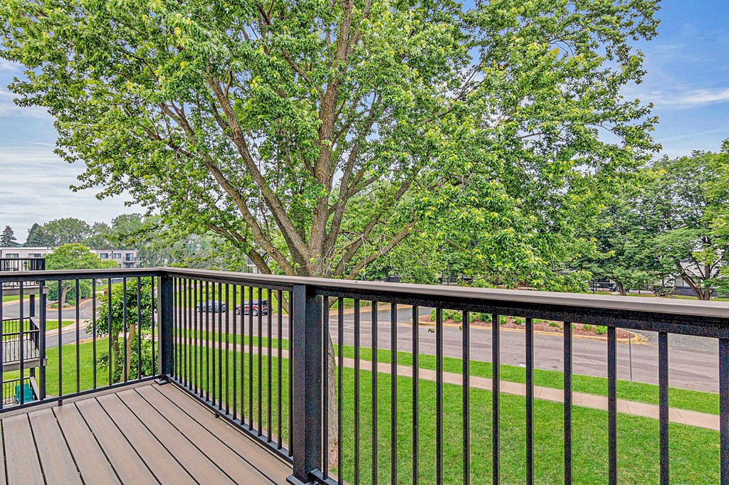 A tree is in the background of a balcony.
