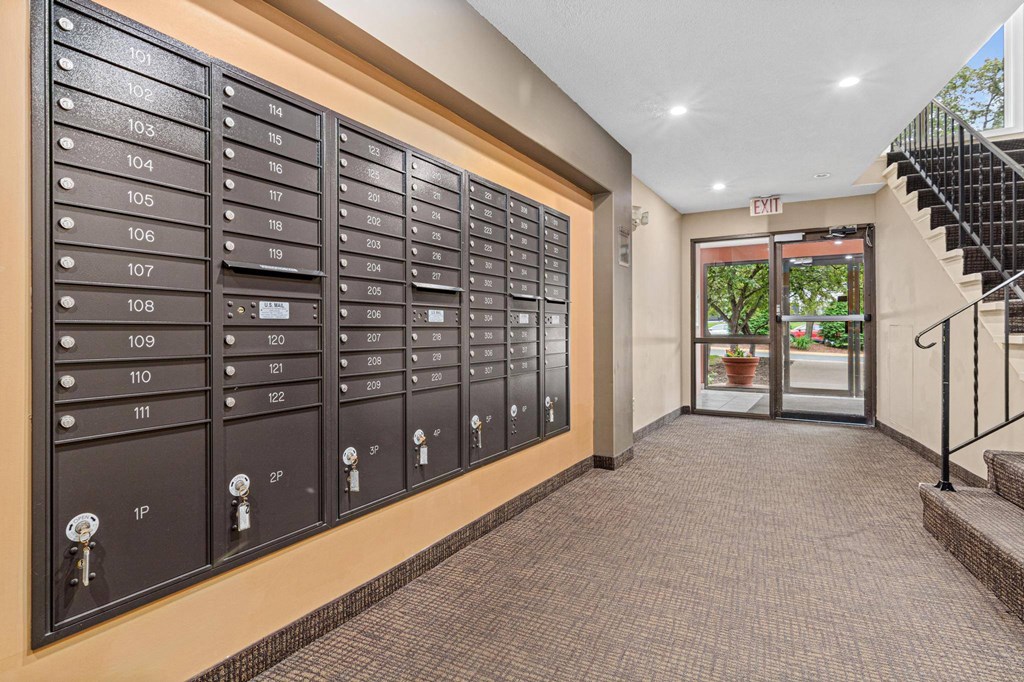 A long row of mailboxes are lined up on a wall.
