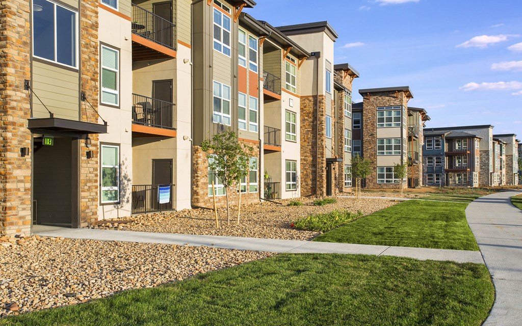 Parkhouse courtyard with green grass, rock beds and concrete walking path