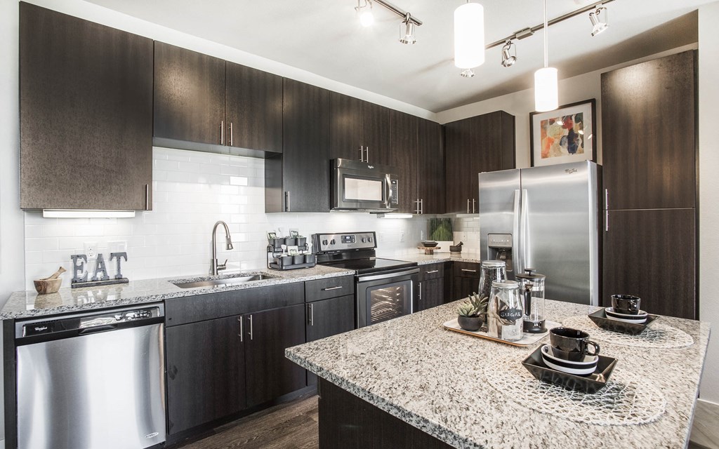 Kitchen with center island, dark wood cabinets, granite countertops and stainless steel appliances