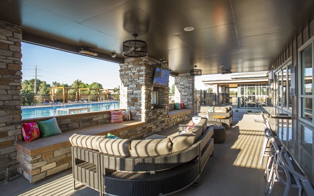 Furnished outdoor lounge area next to pool, with sectional couch and television