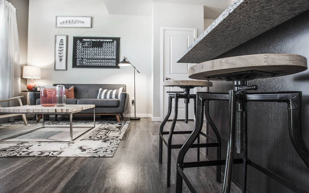 Low angle view of barstools at kitchen island, sofa and coffee table in background