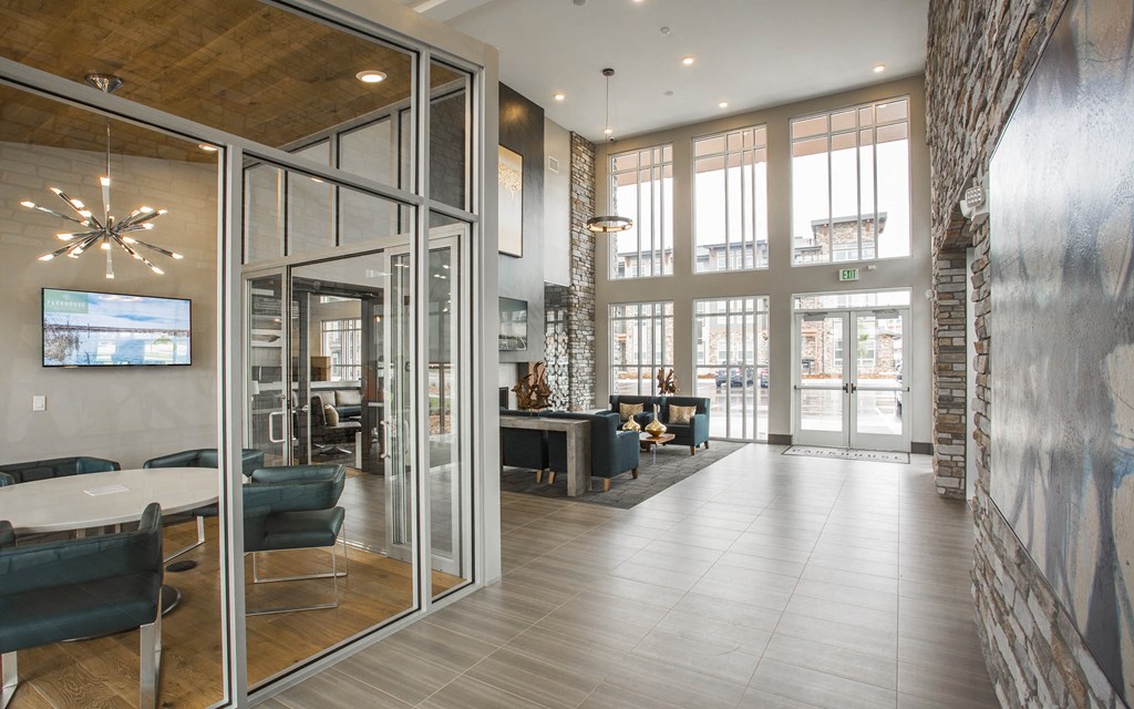 Lobby area with private meeting space surrounded by glass walls, lounge area with arm chairs