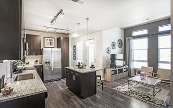 Open kitchen and living room with small center island, dark wood cabinets and granite countertops, furnished living room space - Photo Gallery 2