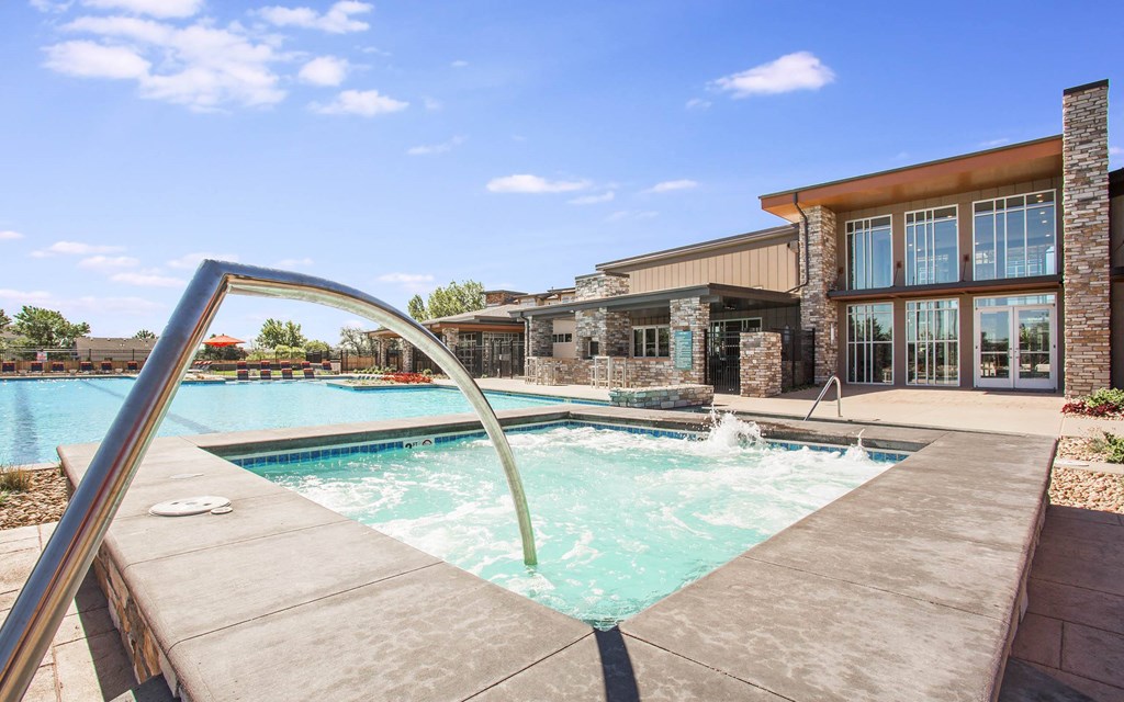 Outdoor hot tub next to outdoor pool, with long curved railing