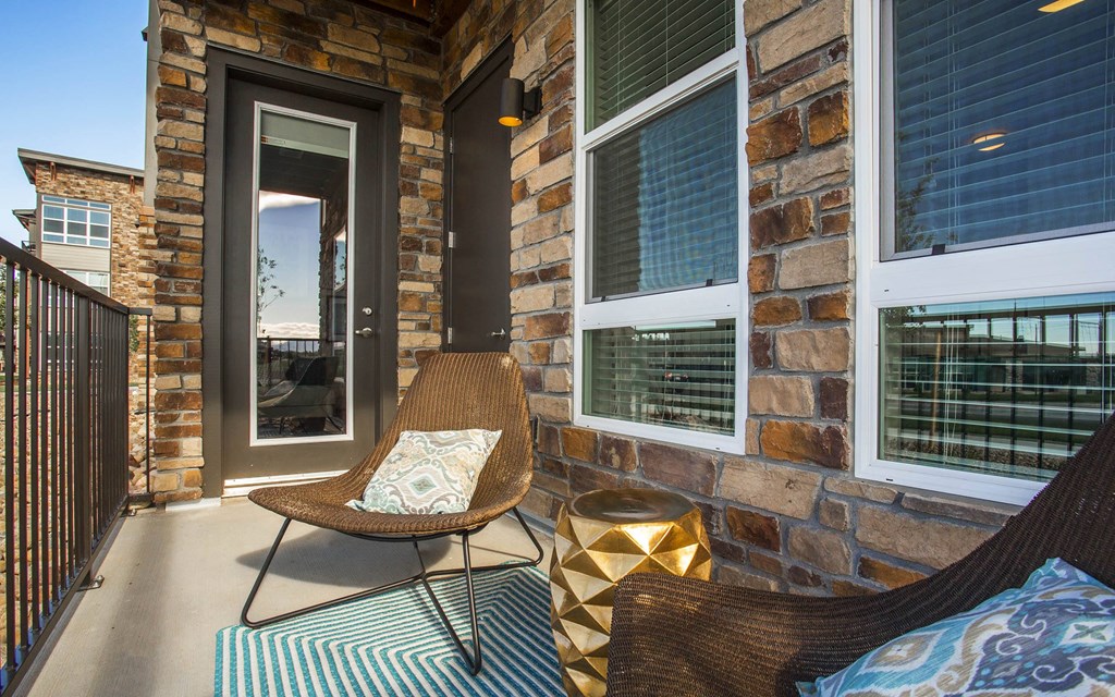 Private balcony with lounge chairs, railing, and door leading into apartment