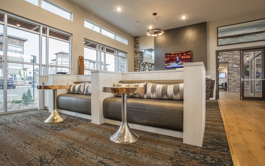 Stadium seating style chairs with small tables in front, facing television in clubhouse