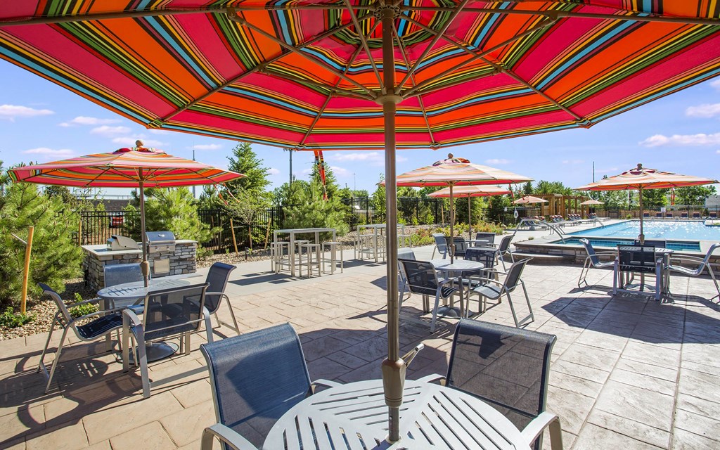 Circular four person tables with large red umbrellas next to outdoor pool