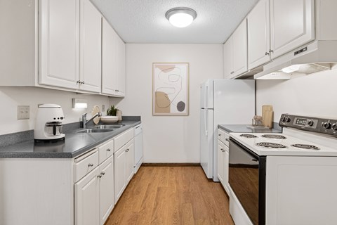 A kitchen with white cabinets and a wooden floor.