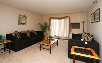 Furnished living room with two black sofas, coffee table and sliding glass door - Photo Gallery 6