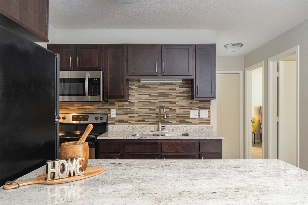 a kitchen with dark wood cabinets and a marble counter top