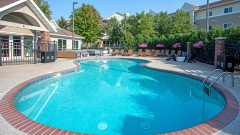 a large pool with chairs and a building in the background