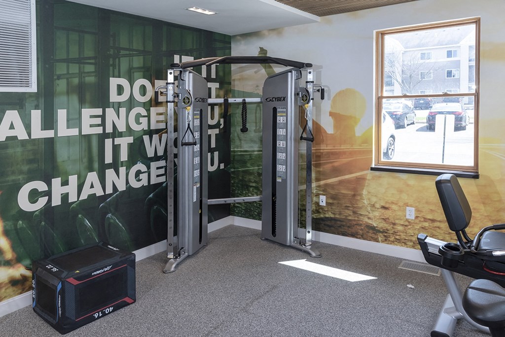 a gym with exercise equipment and a wall with a motivational quote