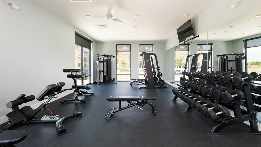 A spacious gym with a variety of equipment including treadmills, stationary bikes, and weight machines.