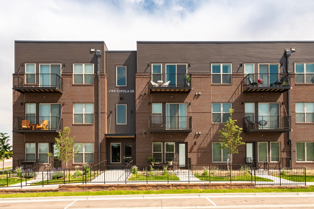 Apartment building with balconies and black railings.