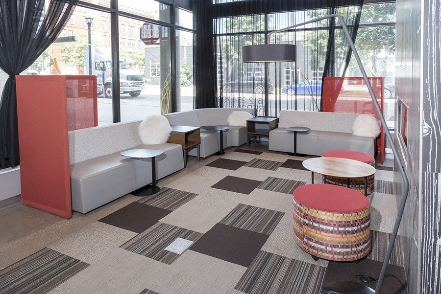 a seating area with couches and stools in front of a window