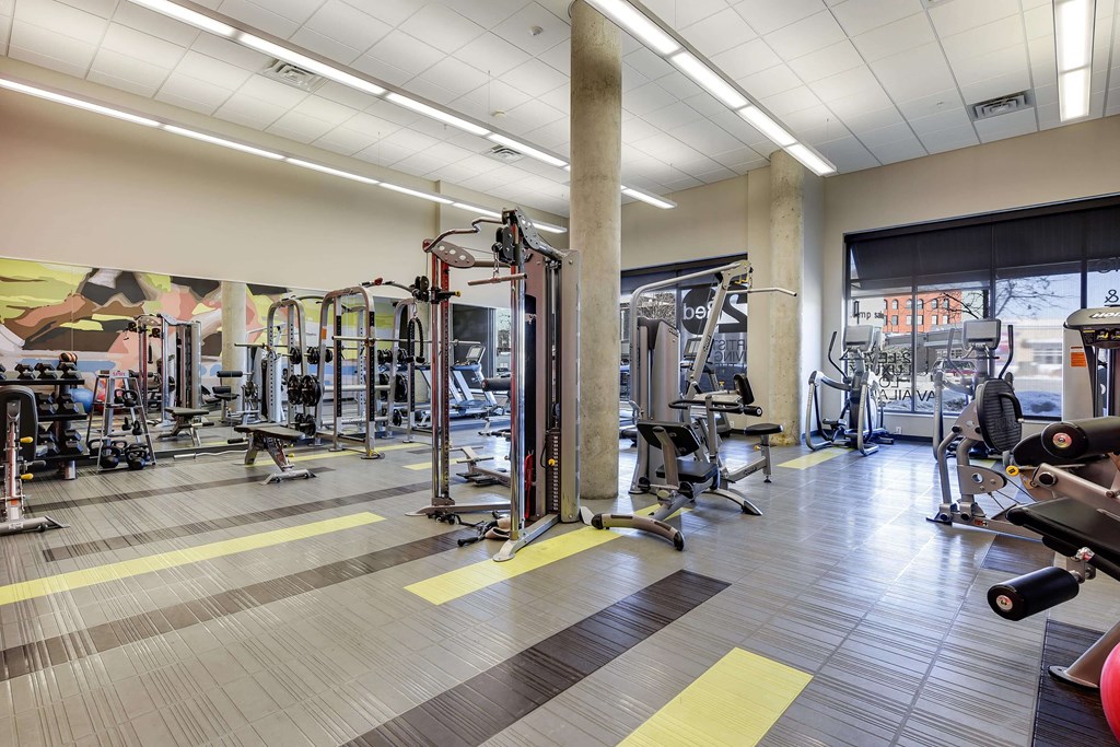 Full fitness center equipped with cardio and strength training machines atop tile flooring.