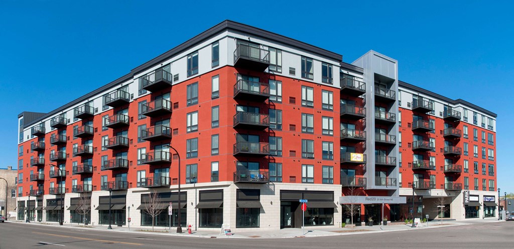 Exterior of Red 20 Apartments; a red and white building with black balconies.