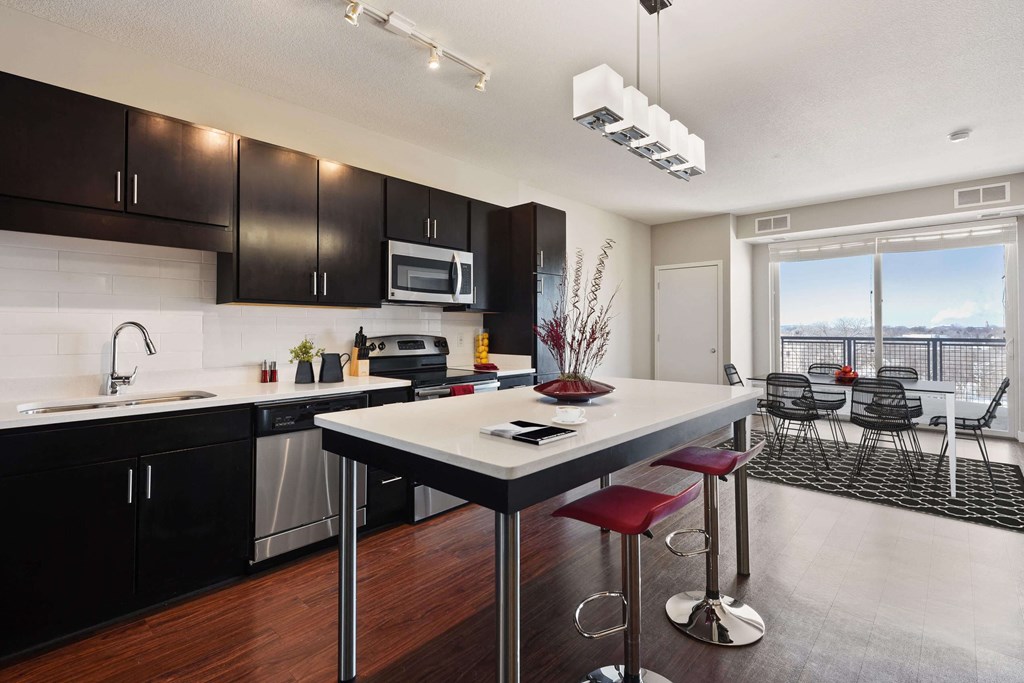 Bright and spacious kitchen with stainless steel appliances, pendant lighting above the island, and gorgeous view of the dining area.