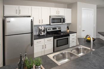 Sleek and modern kitchen with stainless steel finishes and a breakfast bar for casual dining. - Photo Gallery 3