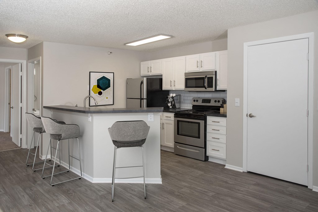 Modern kitchen with open layout, stainless steel appliances, and white cabinetry.