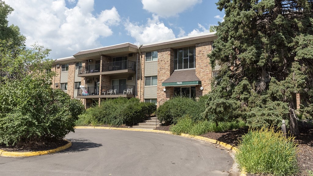 a picture of an apartment building with trees and bushes in front of it