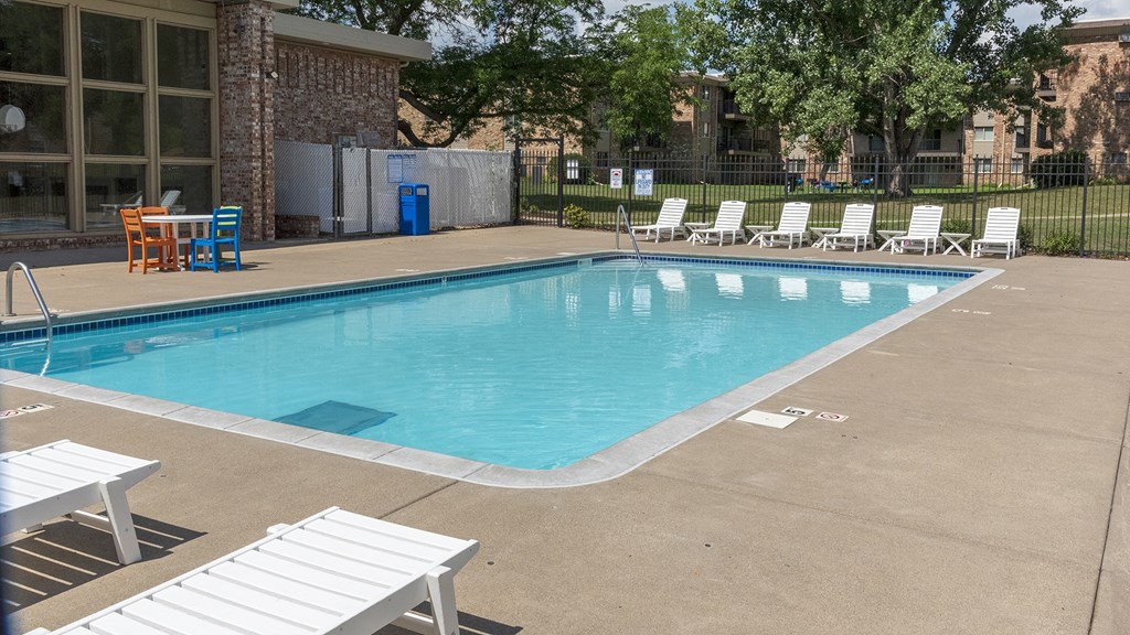 a swimming pool with chaise lounge chairs and trees in the background