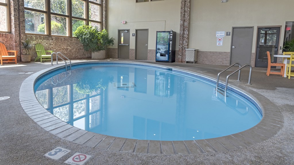 a swimming pool with blue water and brick flooring