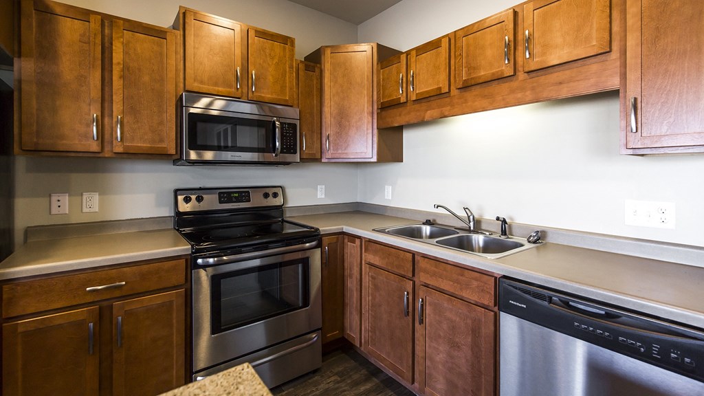 an empty kitchen with wooden cabinets and stainless steel appliances