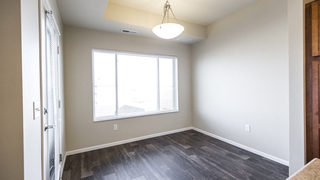 an empty living room with a large window and wood flooring