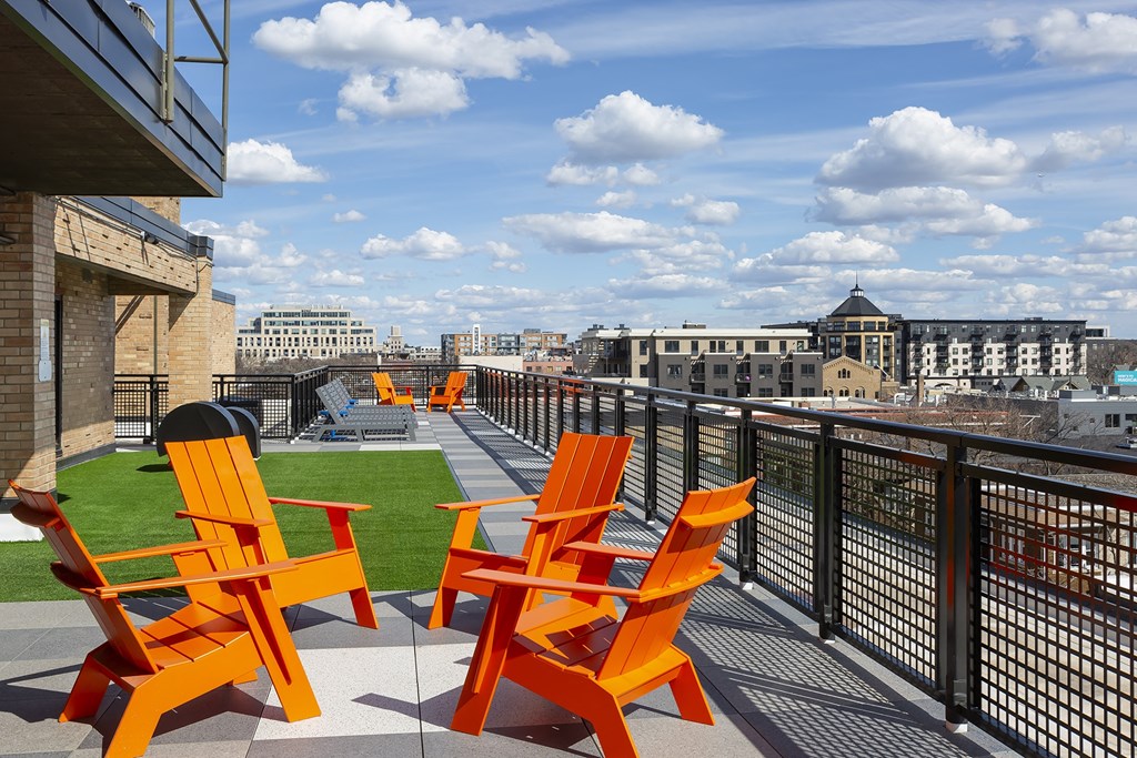 a group of orange chairs on a balcony overlooking a city